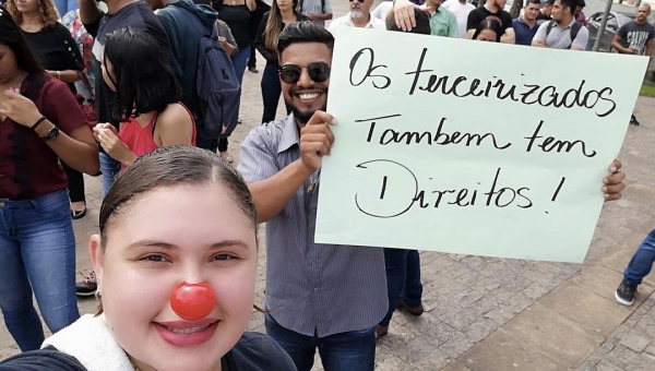 Com nariz de palhaço e cartazes, grupo de trabalhadores terceirizados protesta na frente do Palácio