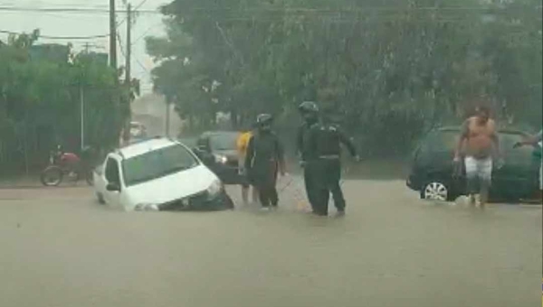 Carro cai em buraco em rua alagada por igarapé durante a chuva desta sexta-feira