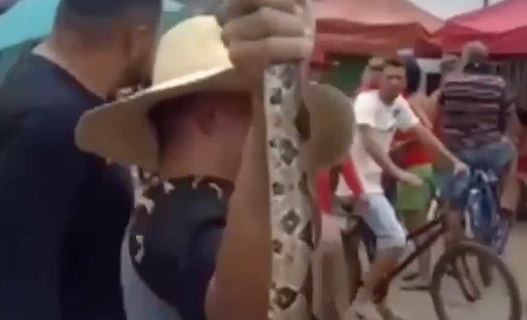 Morador do Aeroporto Velho carrega cobra no pescoço durante cheia do Rio Acre