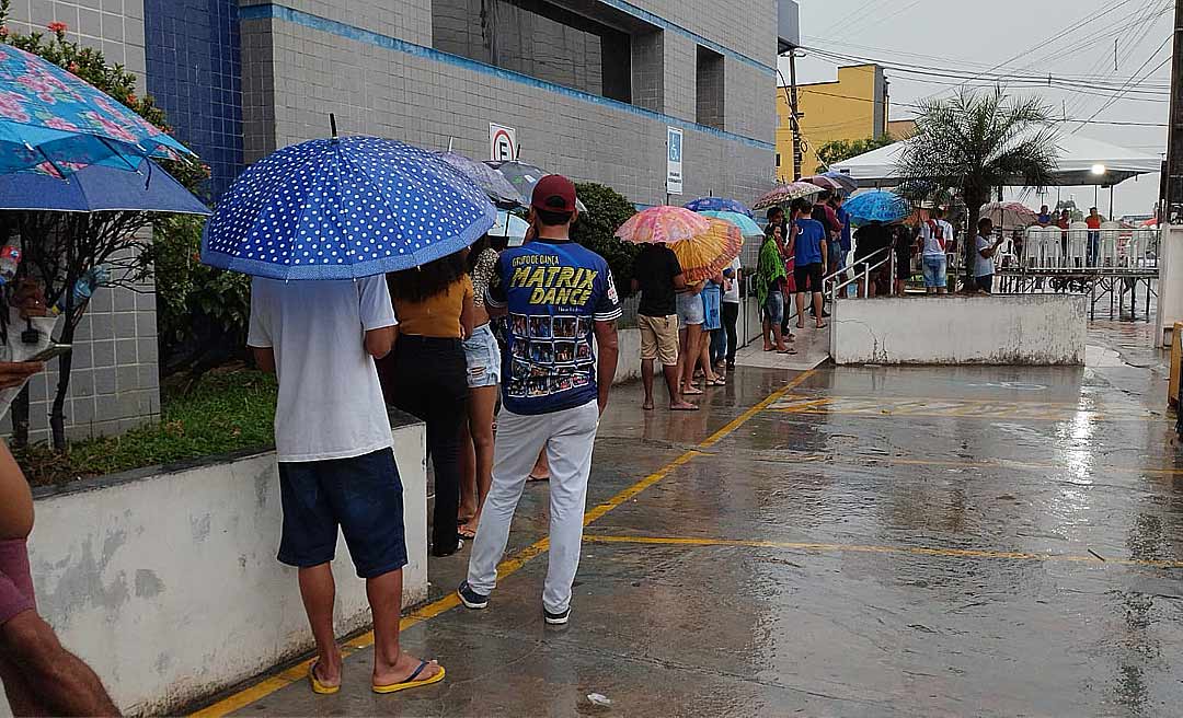 Debaixo de chuva, usuários aguardam atendimento da Caixa em Cruzeiro do Sul