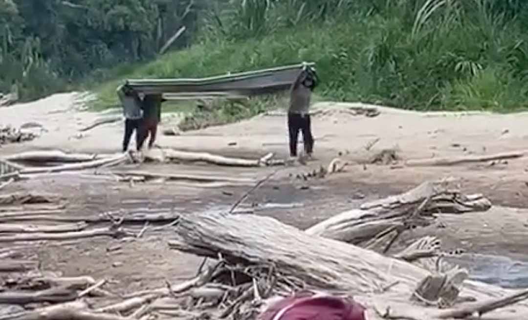 Ribeirinhos carregam barco nas costas no Alto Rio Jordão e cena expõe efeitos das mudanças climáticas na Amazônia